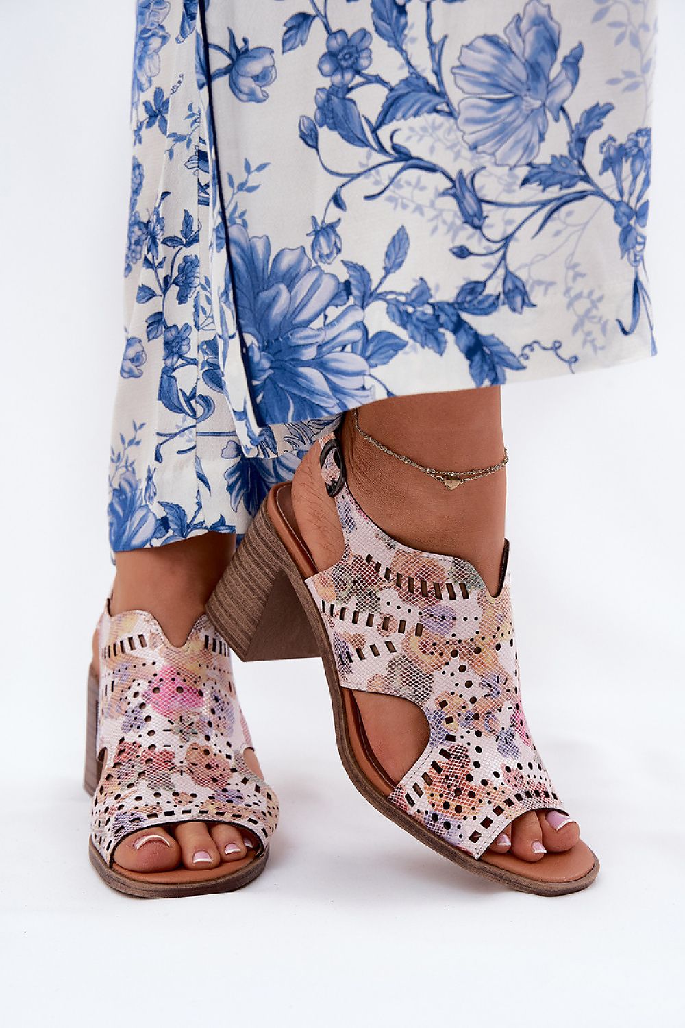 Woman wearing floral dress and pink patterned sandals with block heels.