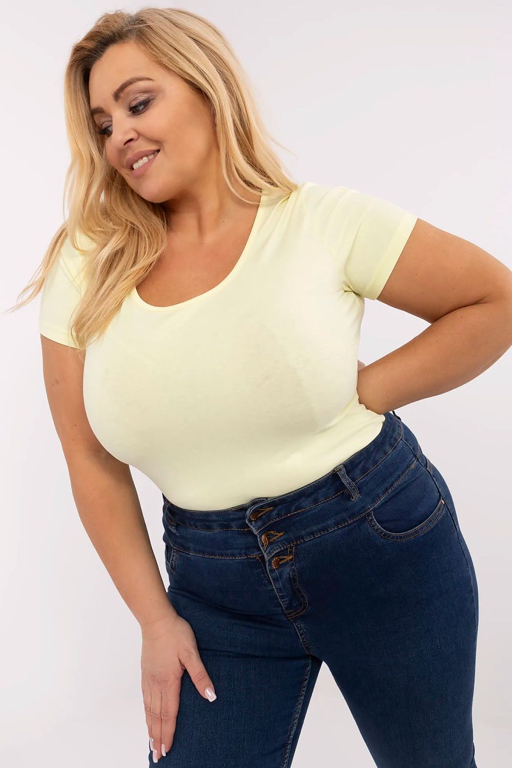 Woman wearing Elvarra Plus Size Cotton Tee in soft yellow, showcasing comfortable fit with short sleeves and round neckline.