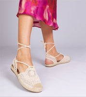 Woman wearing Serella espadrille sandals with braided jute-effect sole and crochet design, paired with a vibrant summer dress.