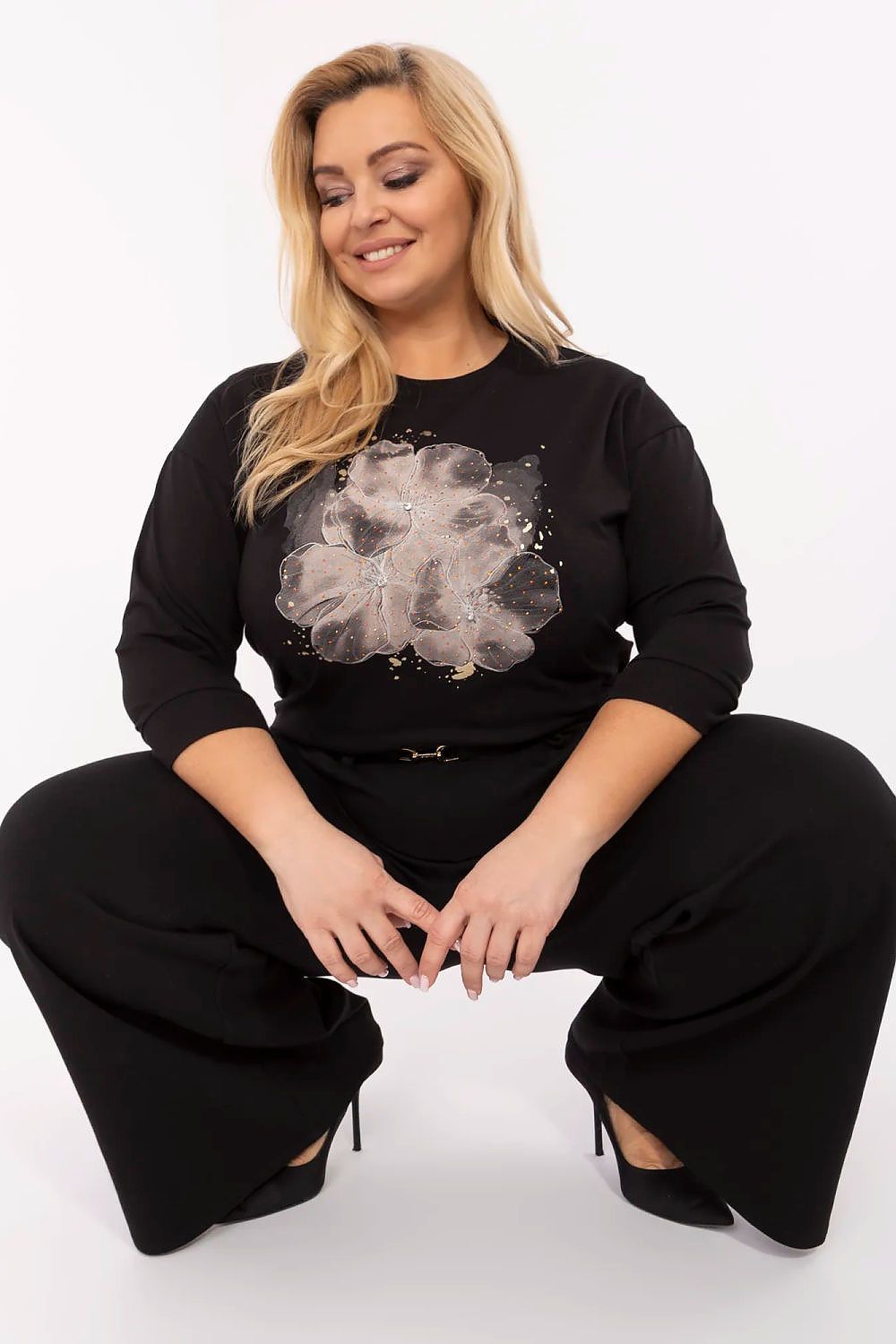 Plus Size Blaire blouse with jet embellishments, round neckline, and three-quarter sleeves, model sitting cross-legged, showcasing style.