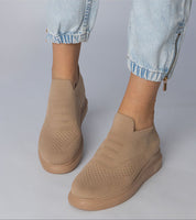 Woman wearing beige Shadowknit Slip-On Sock Sneakers with flexible knit upper and platform sole, paired with light denim jeans.