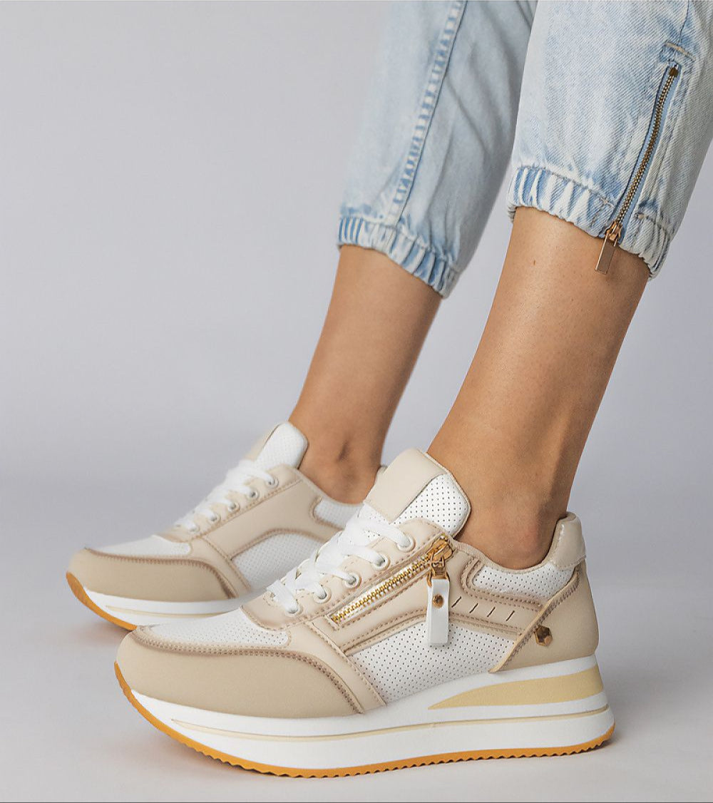 Beige and white zip-up sneakers with platform sole worn by person in light denim, featuring side zipper detail for a modern look.