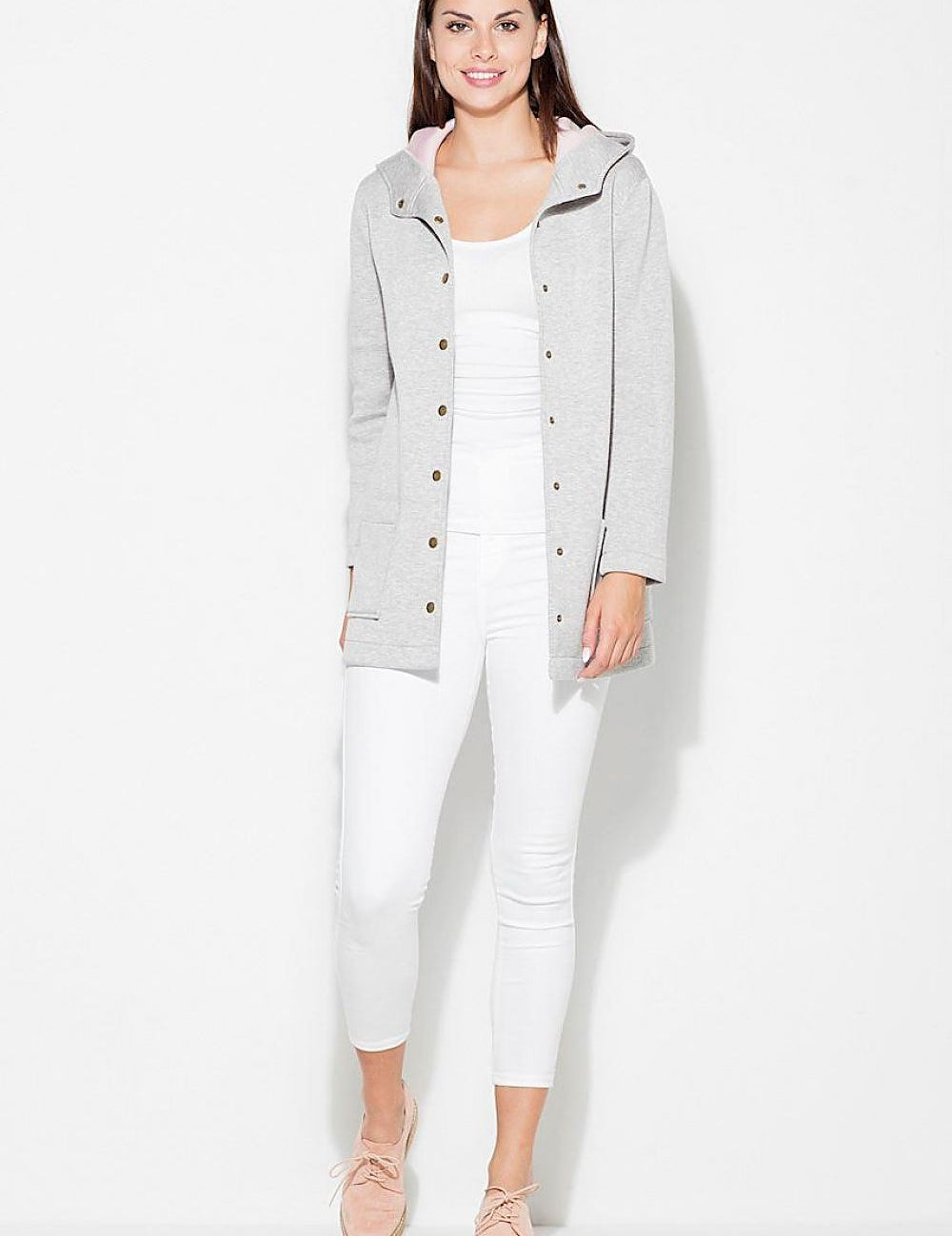 Woman wearing Katrienne Hooded Snap-Front Jacket in grey with decorative press studs, paired with white pants, showcasing a casual outfit.