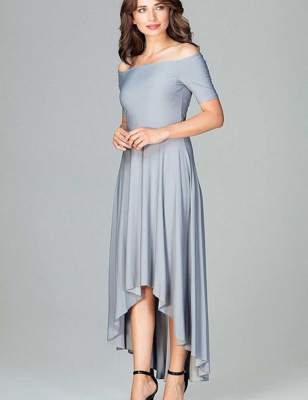 Woman wearing a gray one-shoulder cocktail dress with asymmetrical hemline and black heels, showcasing elegant and chic fashion.