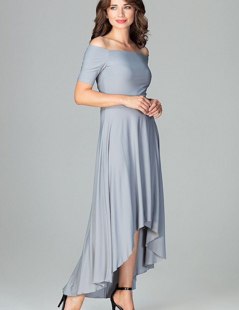 Woman wearing a chic gray off-the-shoulder high-low cocktail dress with a flowing skirt and heels.