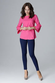 Woman wearing Valenya Zip-Back Frill Blouse in pink with 3/4-length frilled sleeves, paired with blue pants and heels.