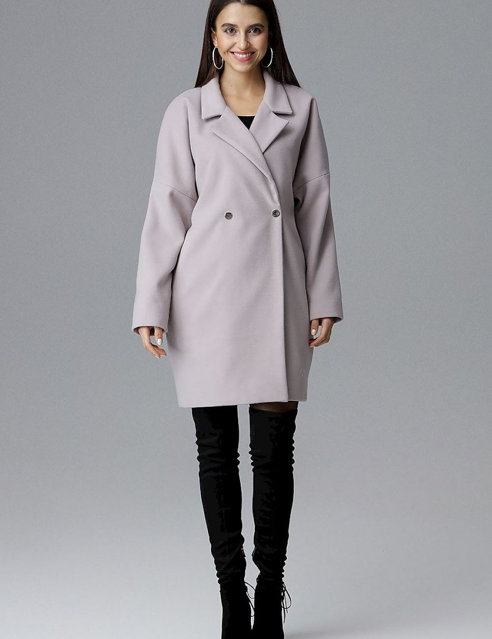 Woman wearing Calverra loose-fit coat with kimono sleeves, double-breasted design, in elegant fabric, perfect for casual or refined outfits.