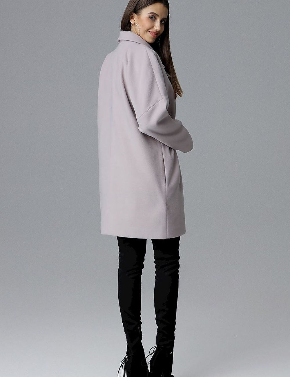 Model wearing a Calverra loose-fit coat with kimono sleeves from the back, double-breasted design, in a soft color, against a gray background.