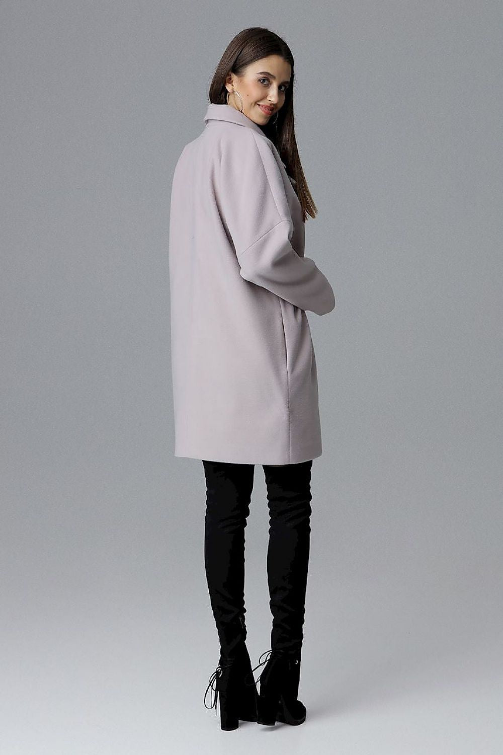 Model wearing a Calverra loose-fit coat with kimono sleeves from the back, double-breasted design, in a soft color, against a gray background.