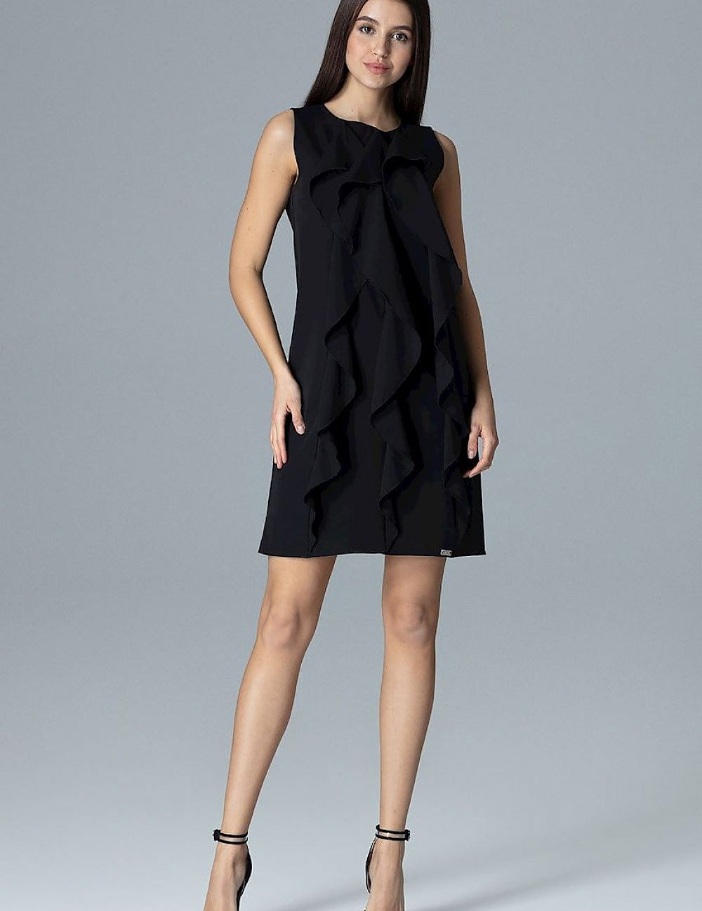 Woman wearing Elvaree Frill Detail Sleeveless Dress, showcasing trapeze cut and vertical frills on a minimalist black design.