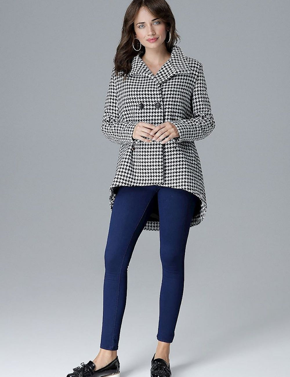 Woman wearing a houndstooth stand-collar jacket with modern zipper details, paired with blue leggings and black platform shoes.