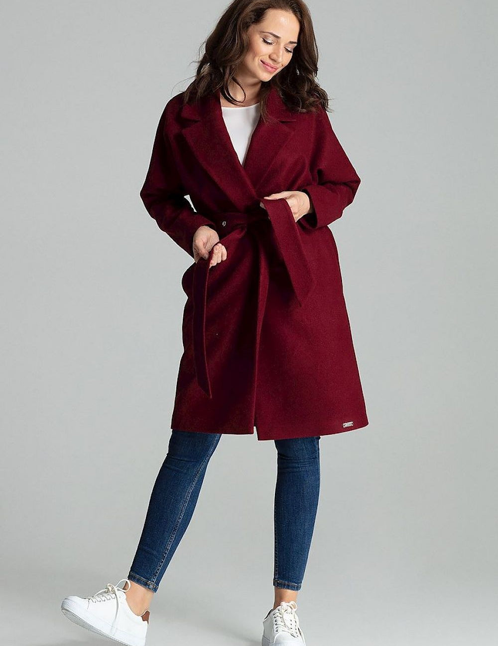 Woman wearing Carivelle Maroon Belted Coat with wide lapels and side pockets, tied at waist, showcasing modern style and elegance.