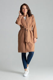 Woman wearing a tan belted coat with wide lapels and jeans, showcasing a stylish casual outfit.