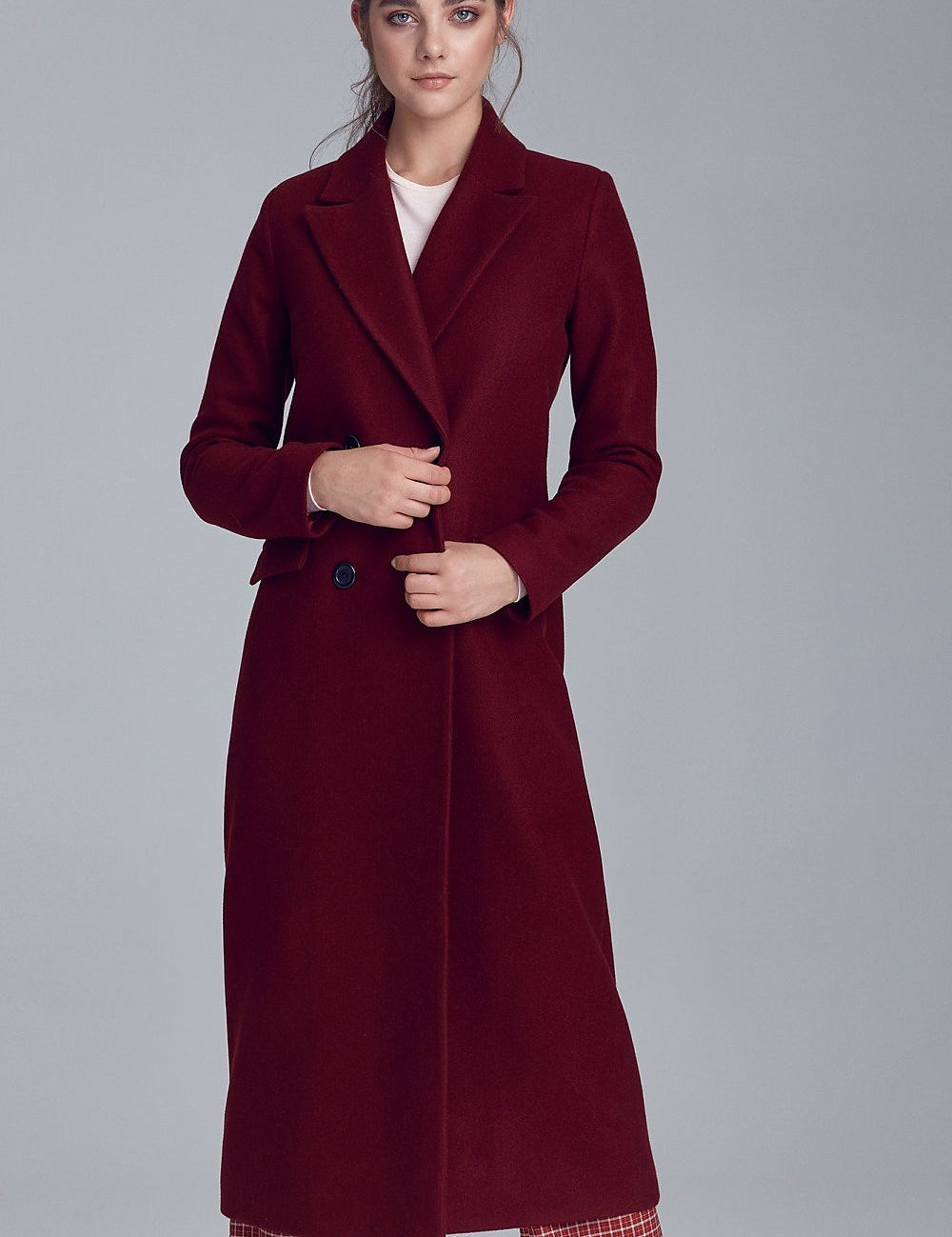 Woman wearing a Marcelaine Long Double-Breasted Wool-Blend Coat in burgundy, featuring a classic collar and functional pockets.