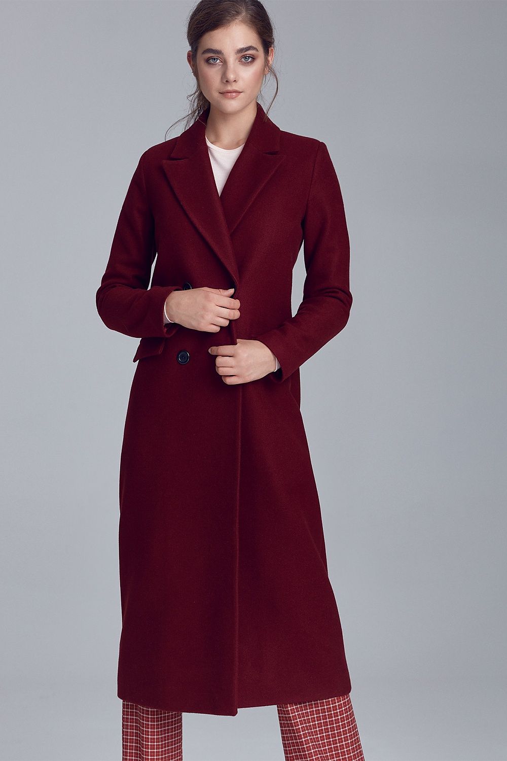 Woman wearing a Marcelaine Long Double-Breasted Wool-Blend Coat in burgundy, featuring a classic collar and functional pockets.