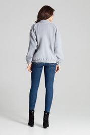 Back view of woman wearing Cerythra Short Grey Loose-Fit Jacket with elasticated cuffs and hem, paired with jeans and boots.