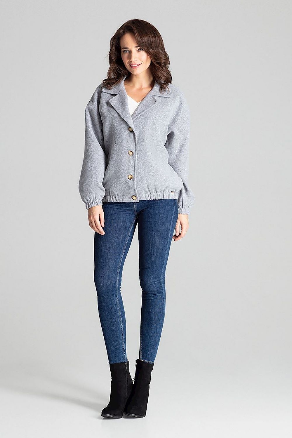 Woman wearing Cerythra Short Grey Loose-Fit Jacket with decorative buttons and elasticated cuffs, ideal for layering and comfort.