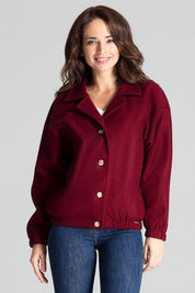 Woman wearing a burgundy loose-fit jacket with decorative buttons and elastic cuffs, styled with jeans for a casual look.