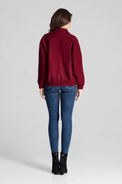 Woman wearing a loose-fit burgundy jacket with elasticated cuffs and hem, styled with blue jeans and black boots. Back view.
