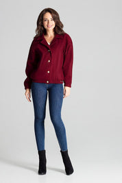 Woman wearing a red loose-fit jacket with decorative buttons, paired with blue jeans and black boots. Casual and stylish outfit.