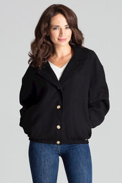 Woman wearing Cerythra short grey loose-fit jacket with decorative buttons and elasticated cuffs, styled casually with jeans.