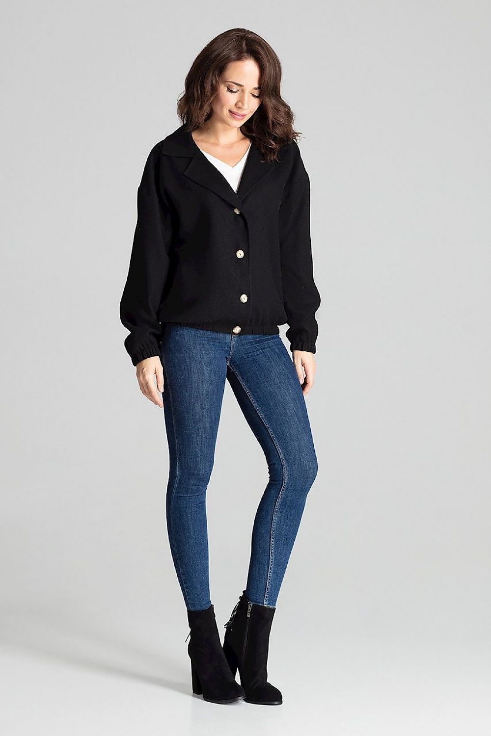 Woman wearing Cerythra short grey loose-fit jacket with jeans and ankle boots, showcasing its relaxed style and decorative buttons.