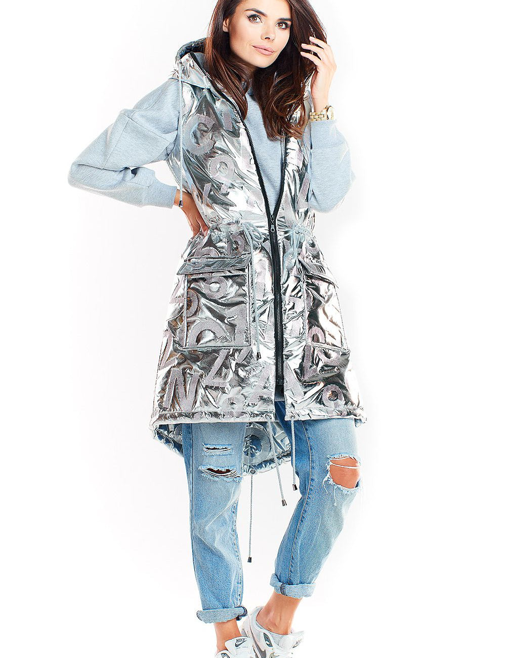 Woman wearing Orlavine Shiny Quilted Hooded Gilet Vest in black and silver, showcasing side pockets and extended back hem.