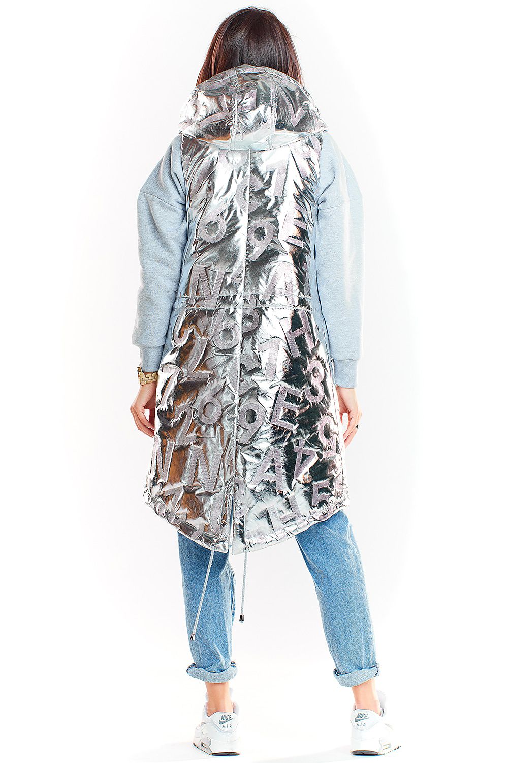 Woman wearing Orlavine shiny quilted hooded gilet vest in black and silver with glossy finish, extended back hem, and side pockets.