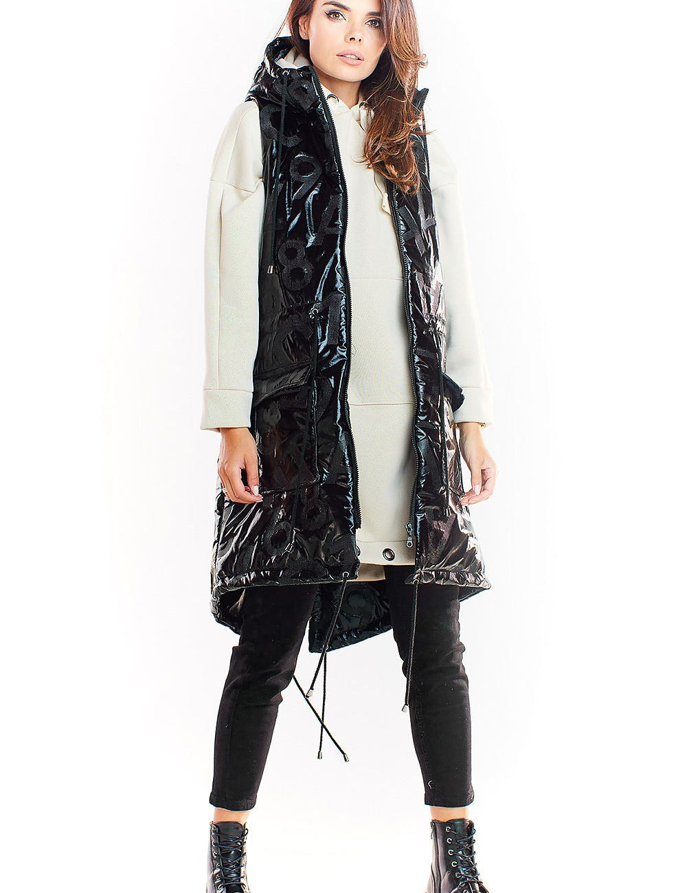 Woman wearing Orlavine Shiny Quilted Hooded Gilet Vest in black and silver with side pockets and extended back hem.