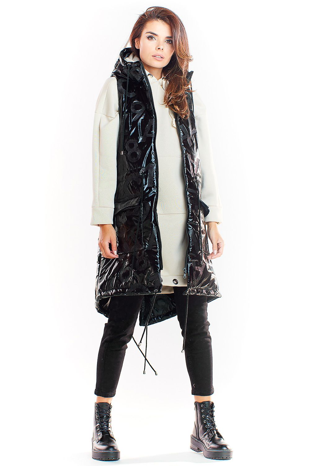 Woman wearing Orlavine Shiny Quilted Hooded Gilet Vest in black and silver with side pockets and extended back hem.