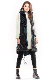 Woman wearing Orlavine Shiny Quilted Hooded Gilet Vest in black and silver with side pockets and extended back hem.