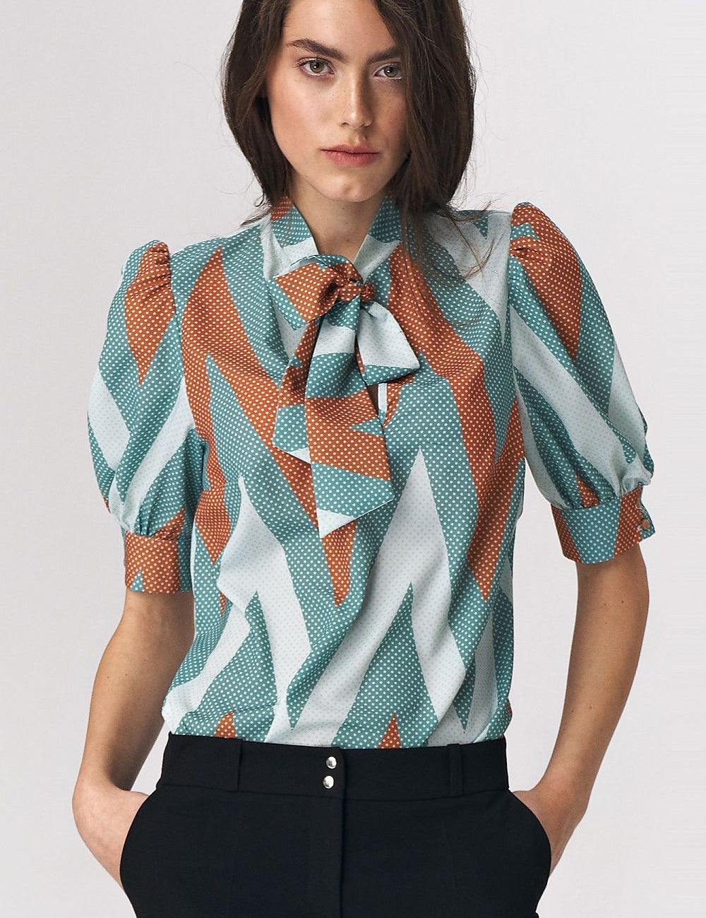 Woman wearing Myressia Zigzag Tie Blouse in turquoise with zigzag pattern and elegant tie neckline, perfect for office attire.