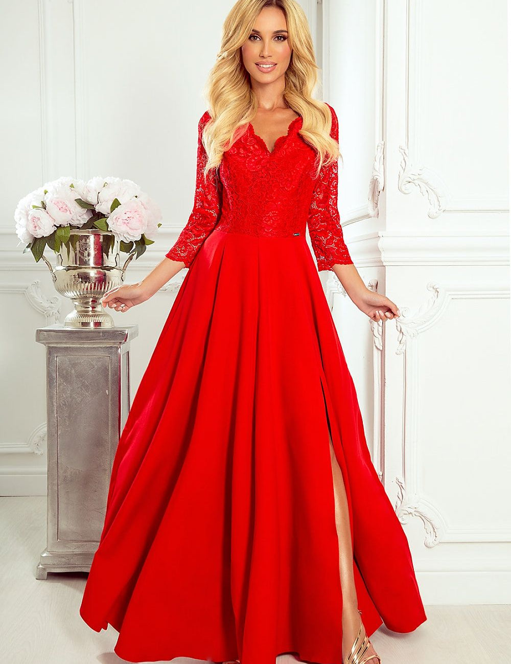 Woman in Ravelle Lace Sweetheart Gown, red floor-length dress with sweetheart neckline, lace, thigh-high slit, and fitted silhouette.