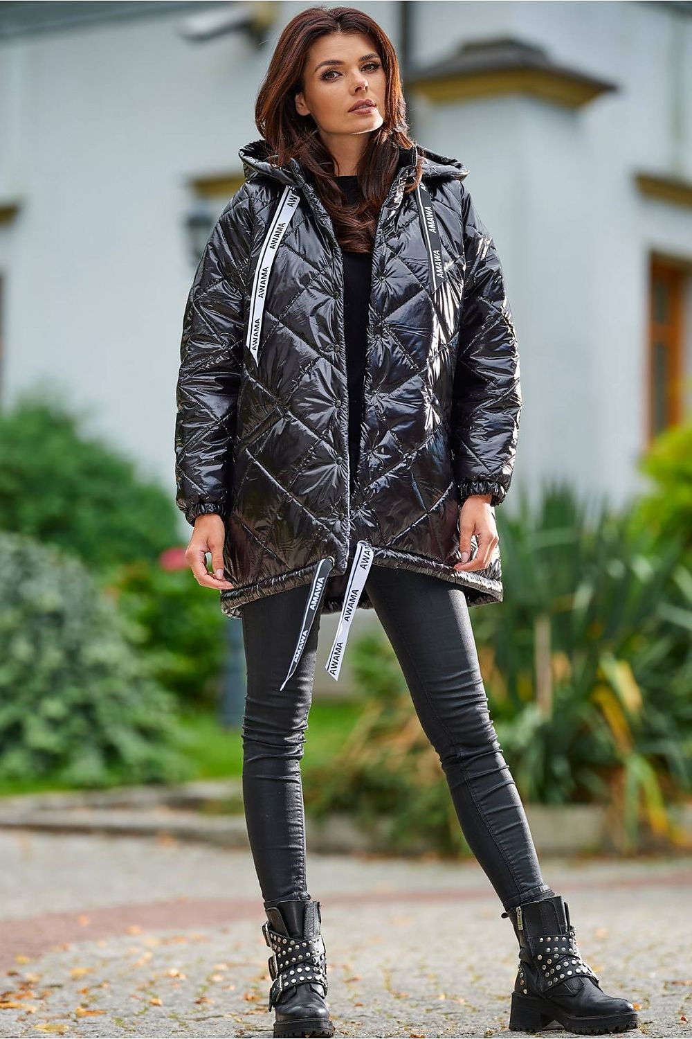 Model wearing Amawa oversized quilted hooded jacket with snap fastening and adjustable logo tape, styled with black pants and boots.