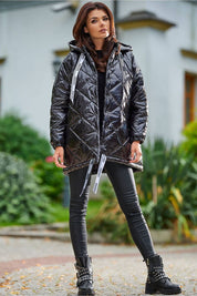 Model wearing Amawa oversized quilted hooded jacket with snap fastening and adjustable logo tape, styled with black pants and boots.