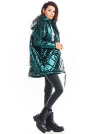 Amawa Oversized Quilted Hooded Jacket in teal, featuring snap fastening, large hood, and decorative logo tape, styled with black pants and boots.