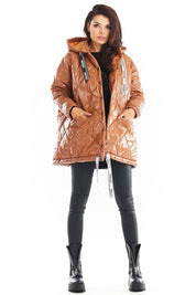 Amawa Oversized Quilted Hooded Jacket with logo tape, snap fastening, and front pockets, worn by model in black pants and boots.