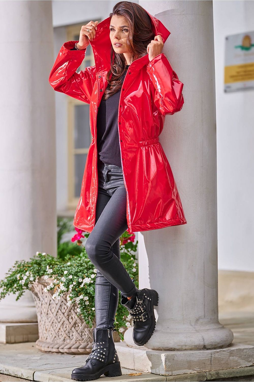 Woman wearing Orlavenne knee-length red vinyl hooded coat with drawstring waist, styled for rain protection and fashion.