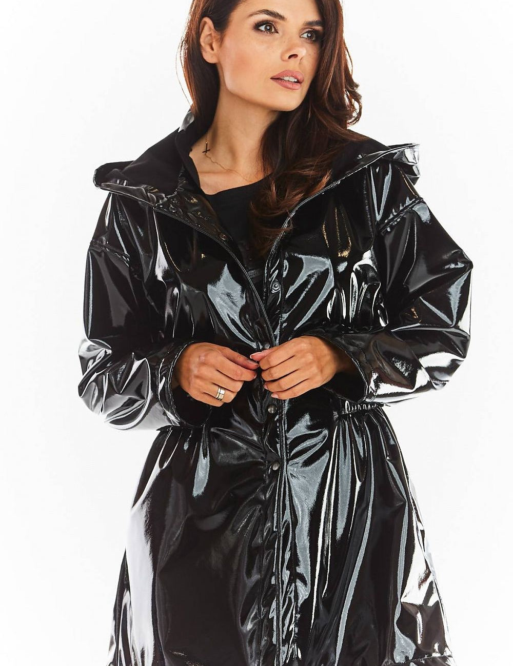 Woman wearing Orlavenne knee-length black vinyl hooded coat with button fastening, showcasing flared hem and adjustable drawstring waist.