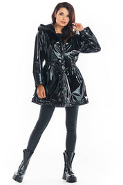 Woman wearing a black Orlavenne knee-length vinyl hooded coat, showcasing its buttoned front and adjustable drawstring waist.