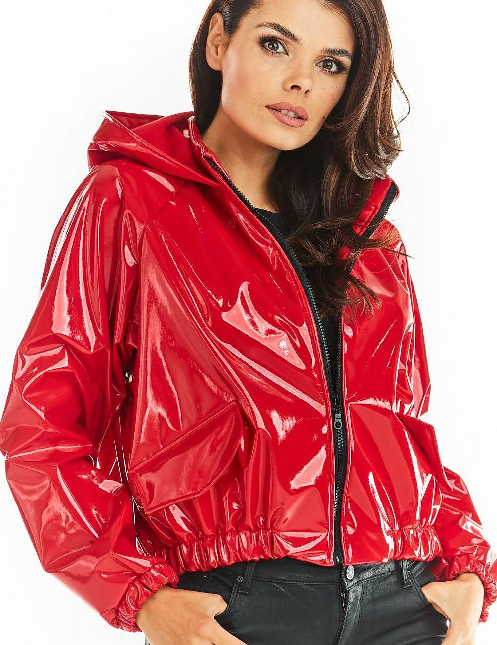 Woman wearing red short vinyl hooded jacket with zip front and pockets, exemplifying street style and functional design.