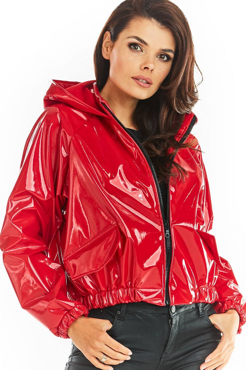 Woman wearing red short vinyl hooded jacket with zip front and pockets, exemplifying street style and functional design.