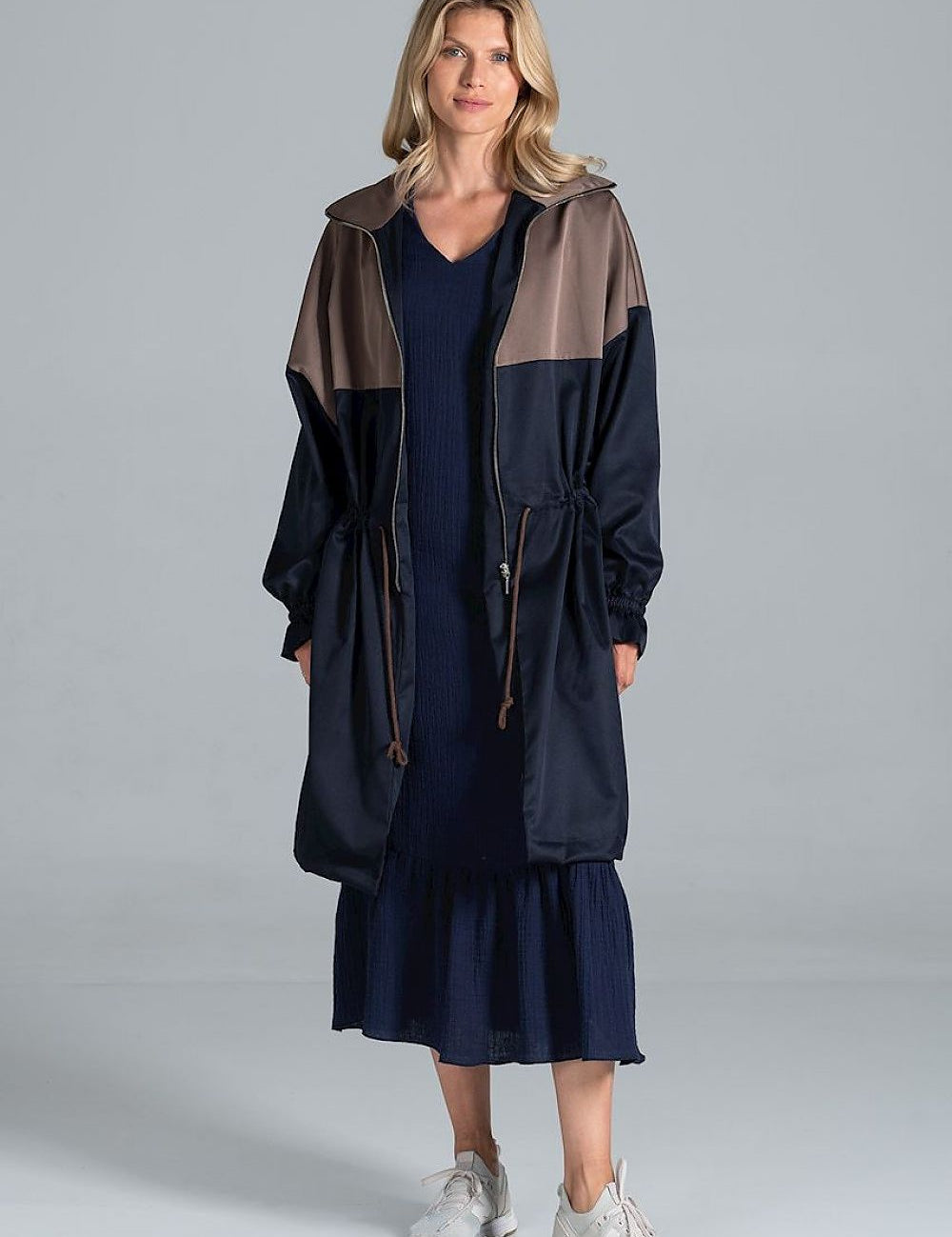 Woman wearing Ardevine Two-Tone Autumn Parka Coat with adjustable drawstring waist and elasticated sleeves, styled over a dress.