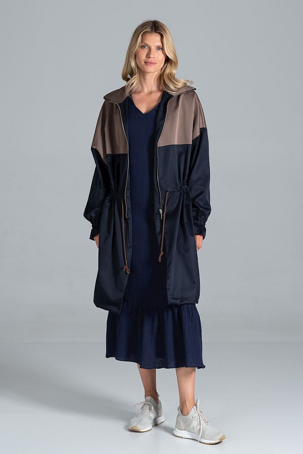 Woman wearing Ardevine Two-Tone Autumn Parka Coat with adjustable drawstring waist and elasticated sleeves, styled over a dress.