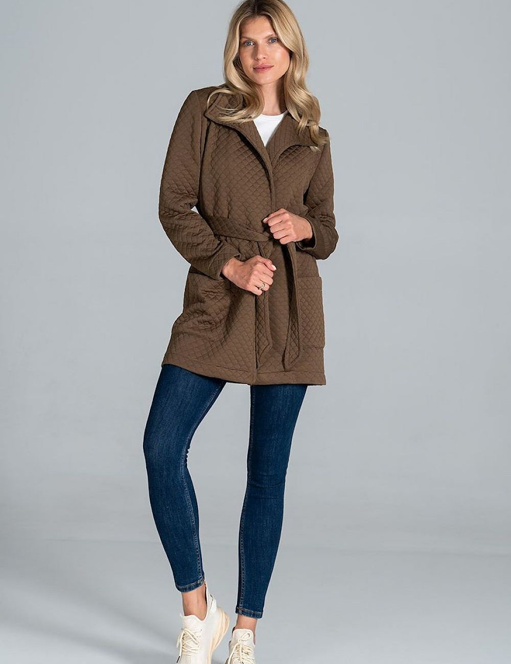 Model wearing Dervelle Short Quilted Belted Coat in brown, featuring front patch pockets and a classic collar, paired with jeans and sneakers.
