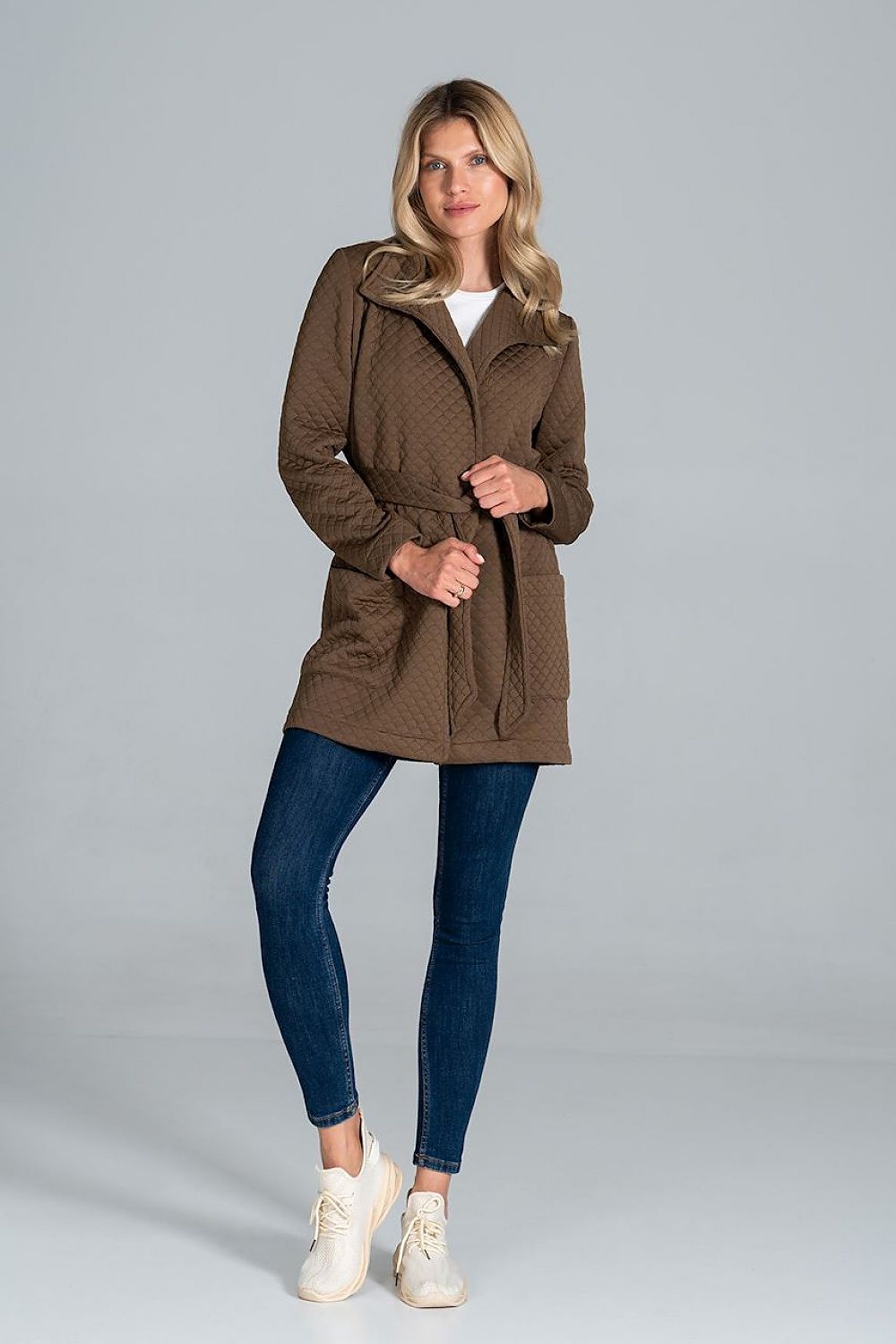 Model wearing Dervelle Short Quilted Belted Coat in brown, featuring front patch pockets and a classic collar, paired with jeans and sneakers.