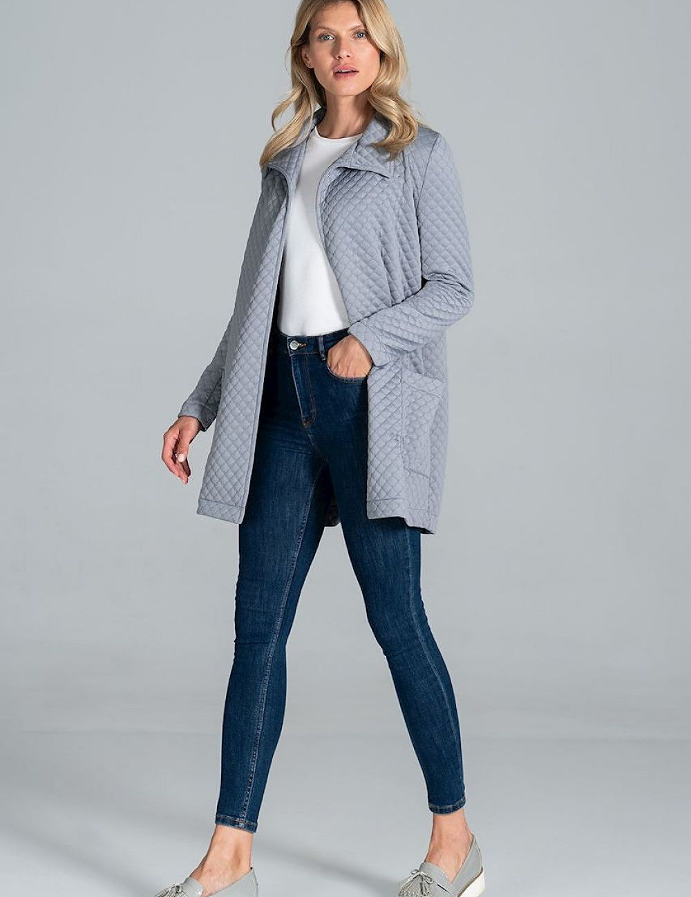 Woman wearing Dervelle short quilted belted coat in light gray, styled casually with jeans and sneakers, showcasing relaxed drape.