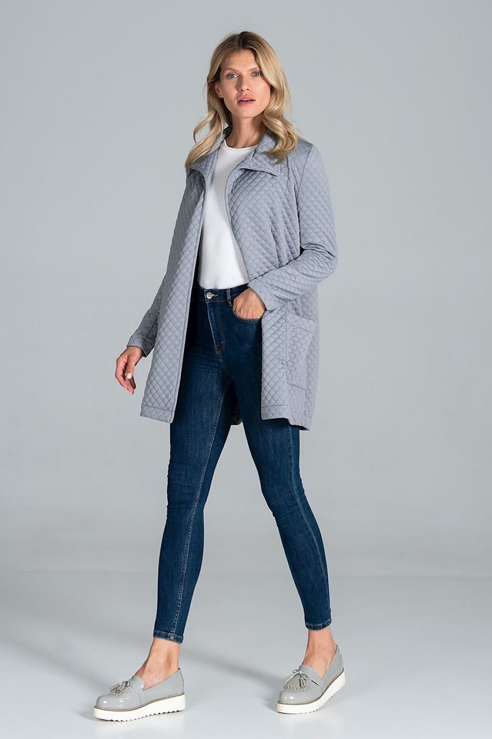 Woman wearing Dervelle short quilted belted coat in light gray, styled casually with jeans and sneakers, showcasing relaxed drape.