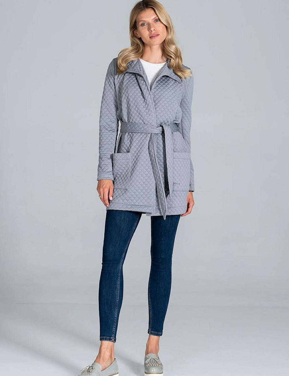 Woman wearing Dervelle short quilted belted coat in light gray, with classic collar and patch pockets, styled with jeans and casual shoes.