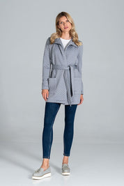 Woman wearing Dervelle short quilted belted coat in light gray, with classic collar and patch pockets, styled with jeans and casual shoes.